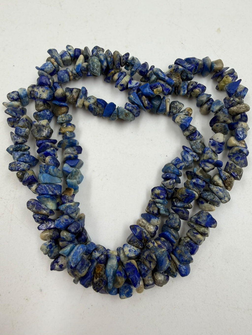 Natural lapis lazuli chip bead necklace held in hand showing texture and color variation