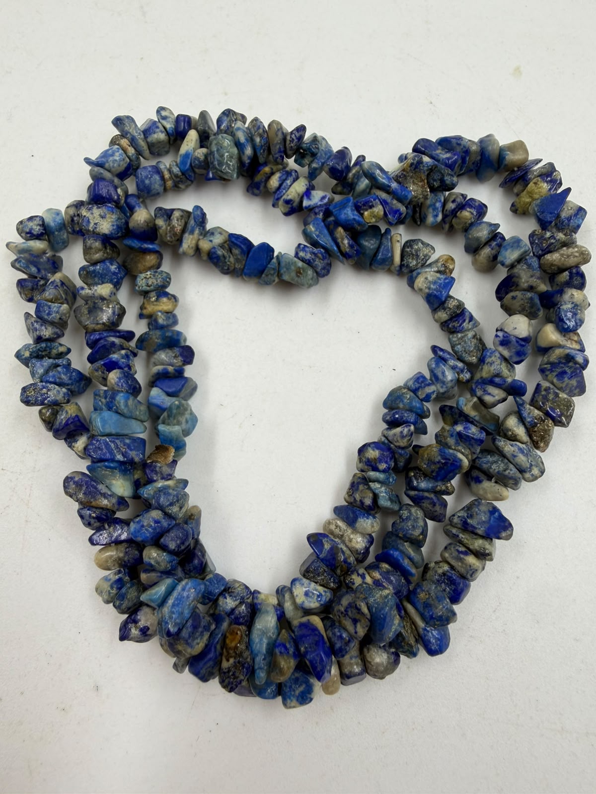 Natural lapis lazuli chip bead necklace held in hand showing texture and color variation