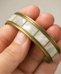 Vintage brass bangle bracelet with mother of pearl inlay worn on woman wrist