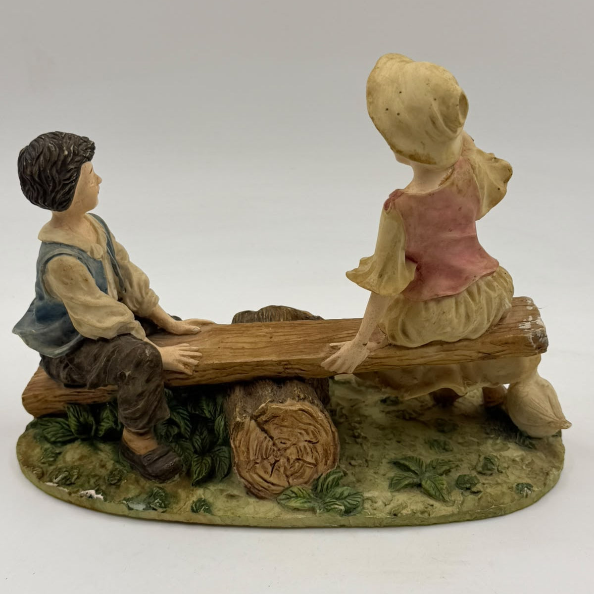 Vintage Victorian resin children seesaw figurine side view with ruler showing 17cm height
