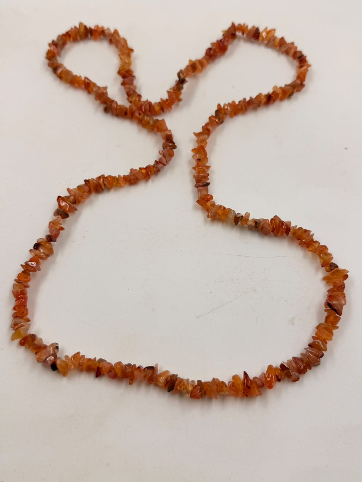 Natural carnelian chip bead necklace full view on white background showing deep orange-red color