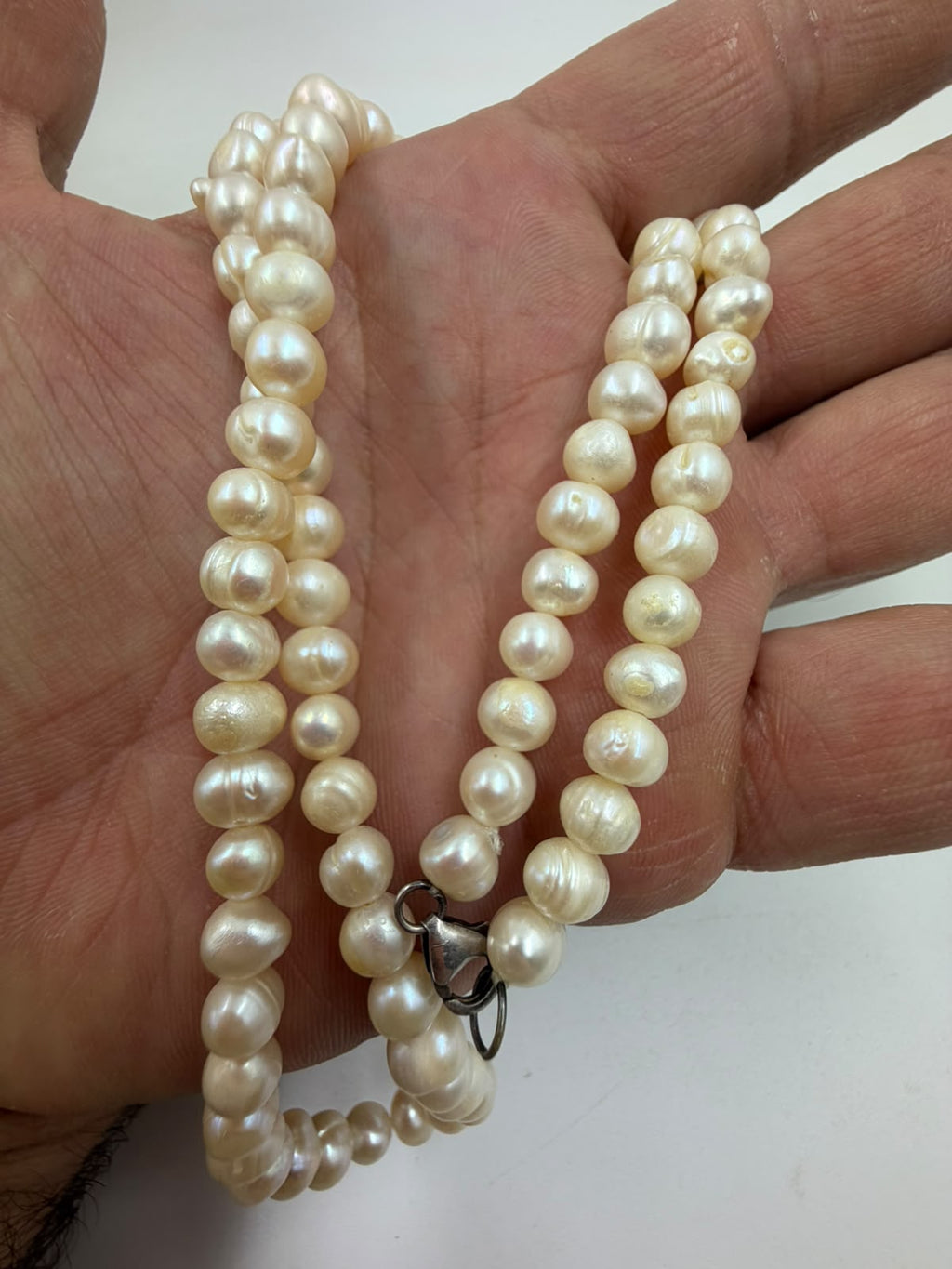 Freshwater pearl necklace laid in hand showing soft nacre luster and natural growth line surface details