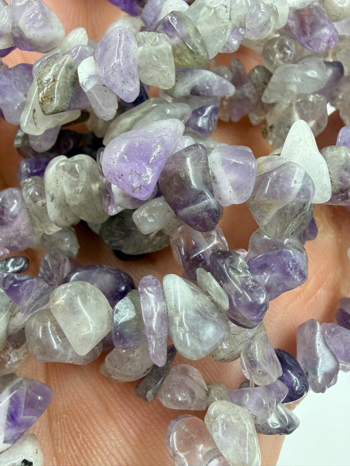 Natural amethyst chips held in hand showing stone texture and mixed purple tones