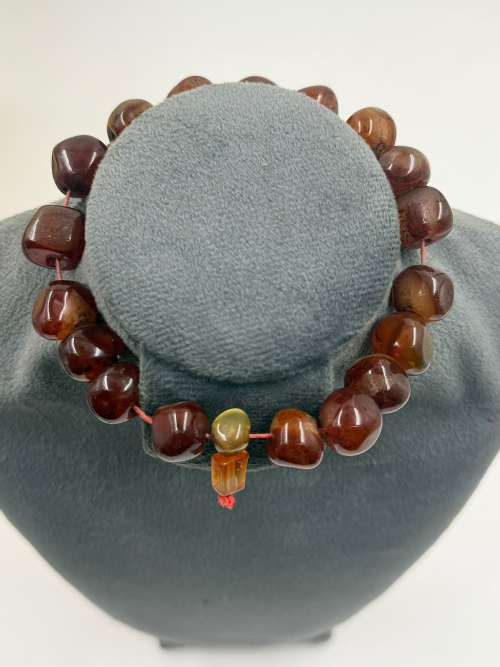 Close-up of natural red brown agate tumbled beads in hand showing translucent honey amber highlights and swirling inclusions