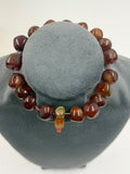 Close-up of natural red brown agate tumbled beads in hand showing translucent honey amber highlights and swirling inclusions