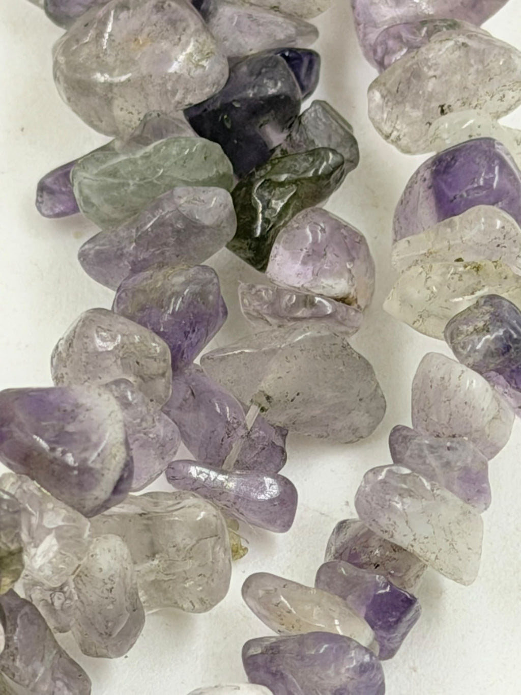 Natural amethyst chip stones close up showing purple lavender and clear crystal colors