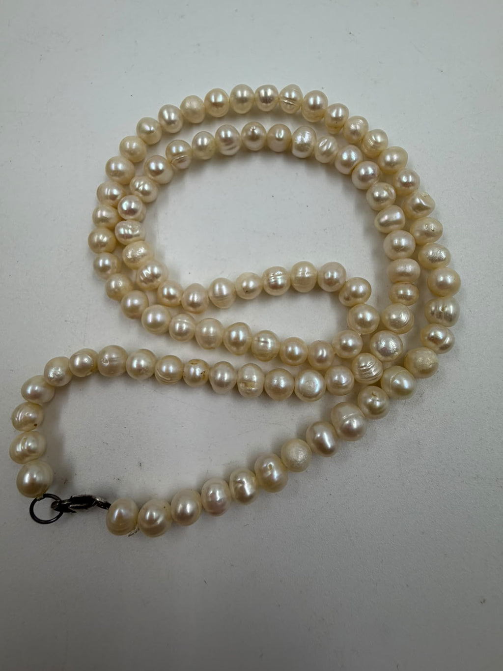 Top view of freshwater pearl necklace coiled showing cream white color with gentle iridescent glow