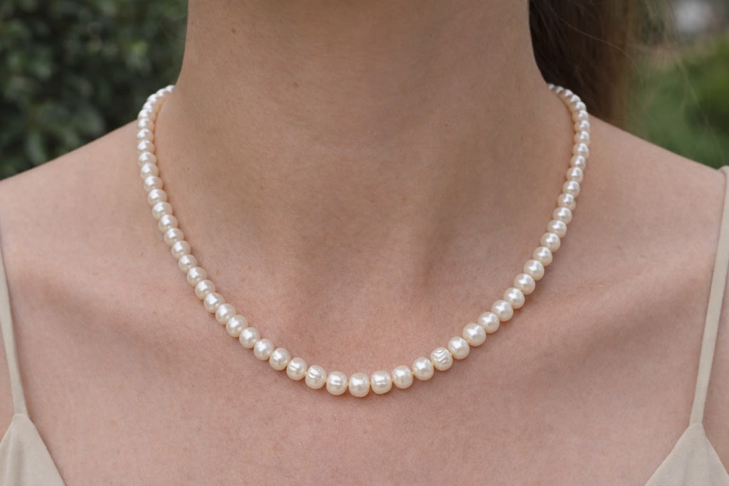 Close-up of freshwater baroque pearl beads on wicker surface showing near-round shape and creamy white color