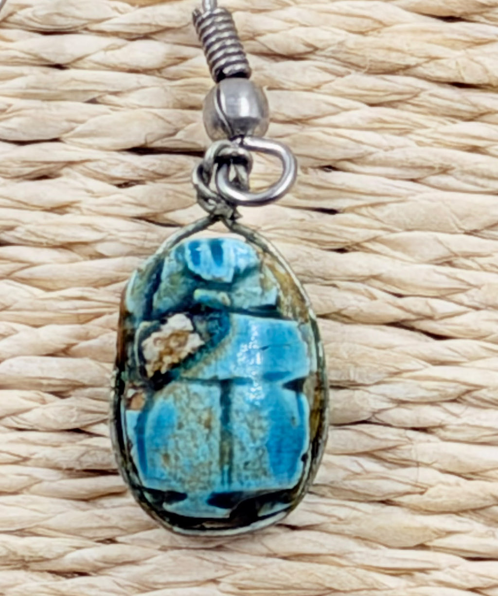 Scarab earrings pair on rattan background - angled view