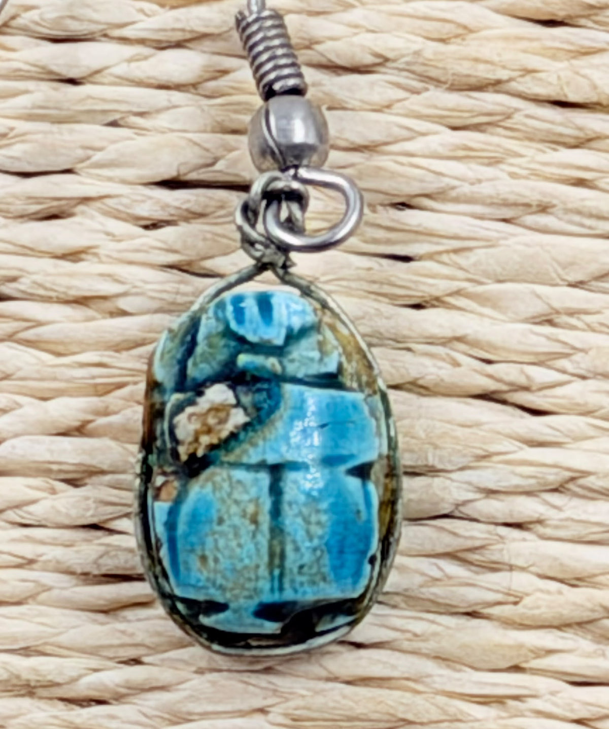 Scarab earrings pair on rattan background - angled view