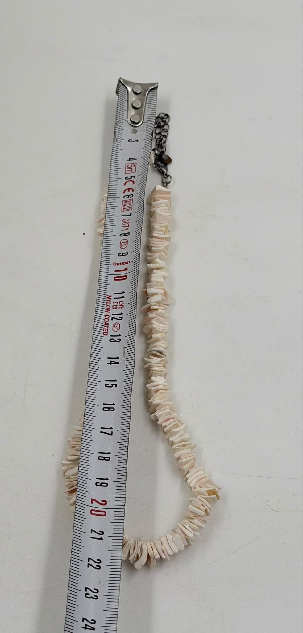 Pink shell necklace next to ruler showing 22cm length