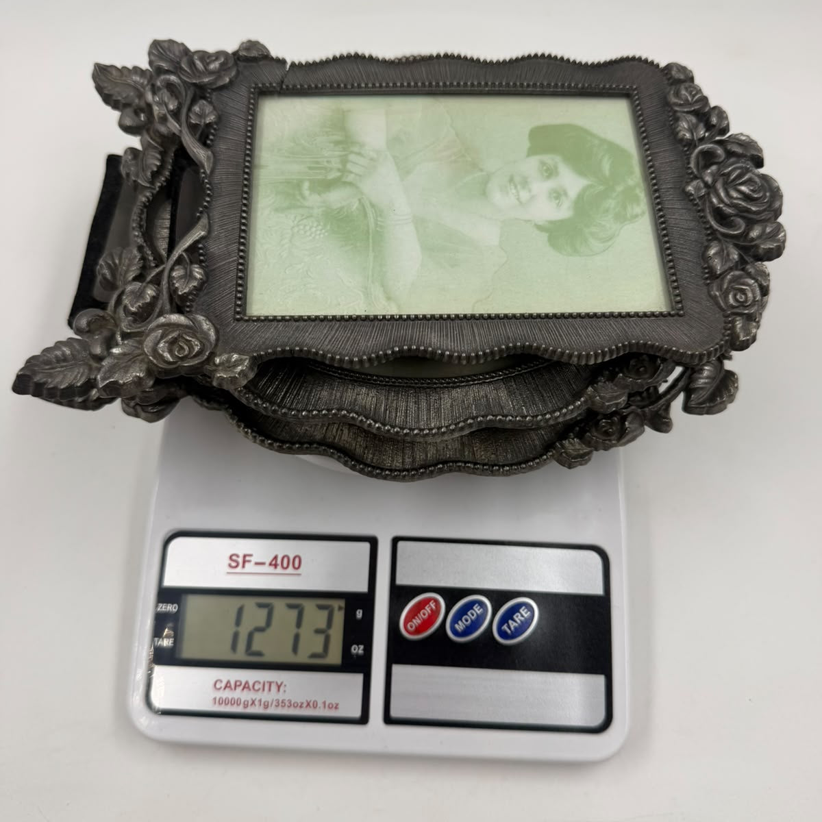 Oval pewter photo frame with ruler showing 20cm height