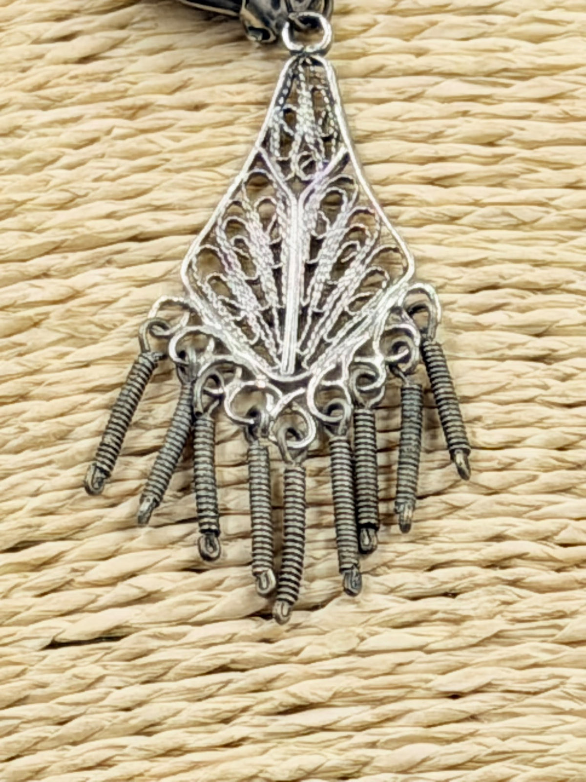 Pair of filigree earrings held in hand showing size reference
