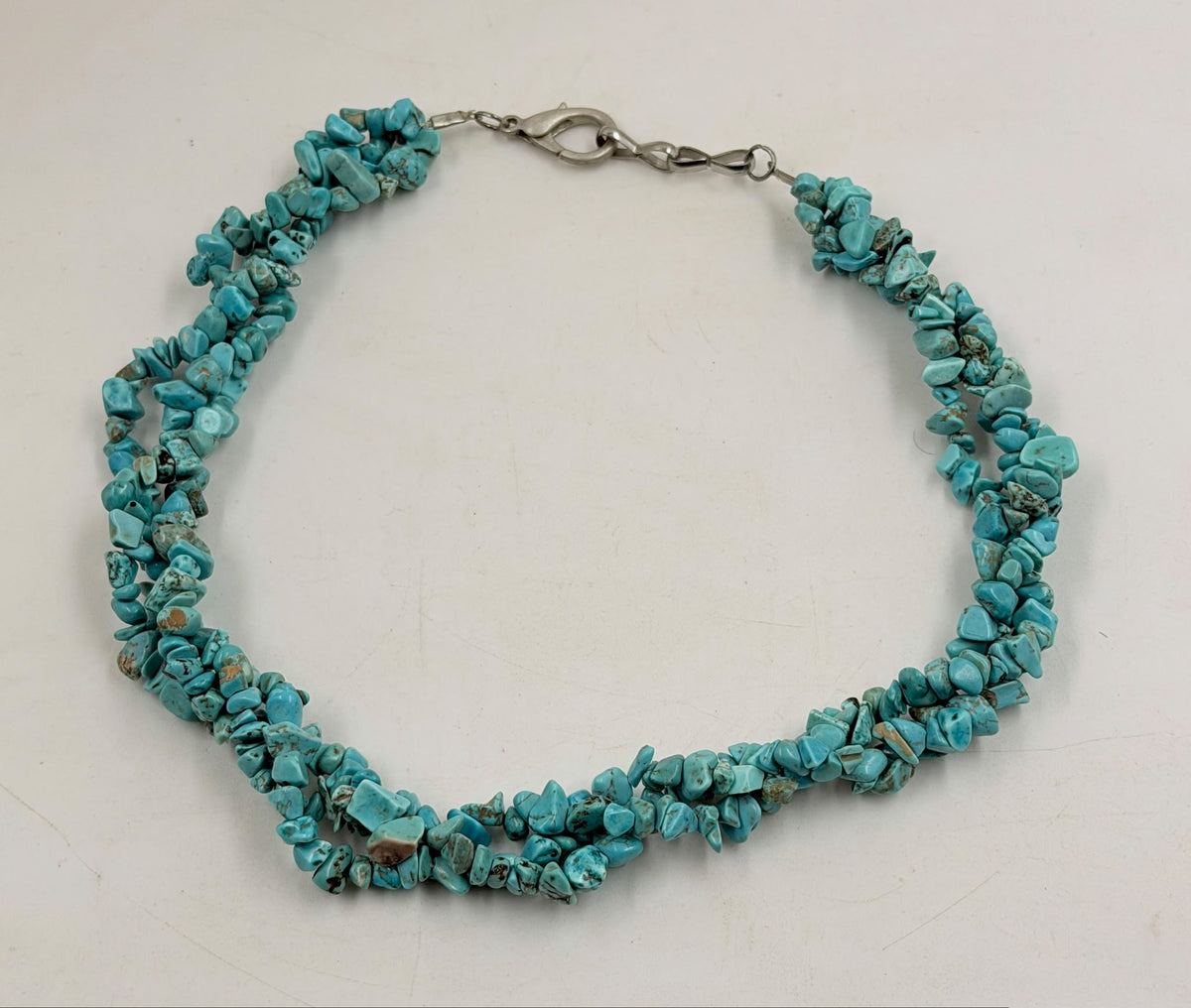 Triple strand turquoise chip stone necklace laid flat on white background