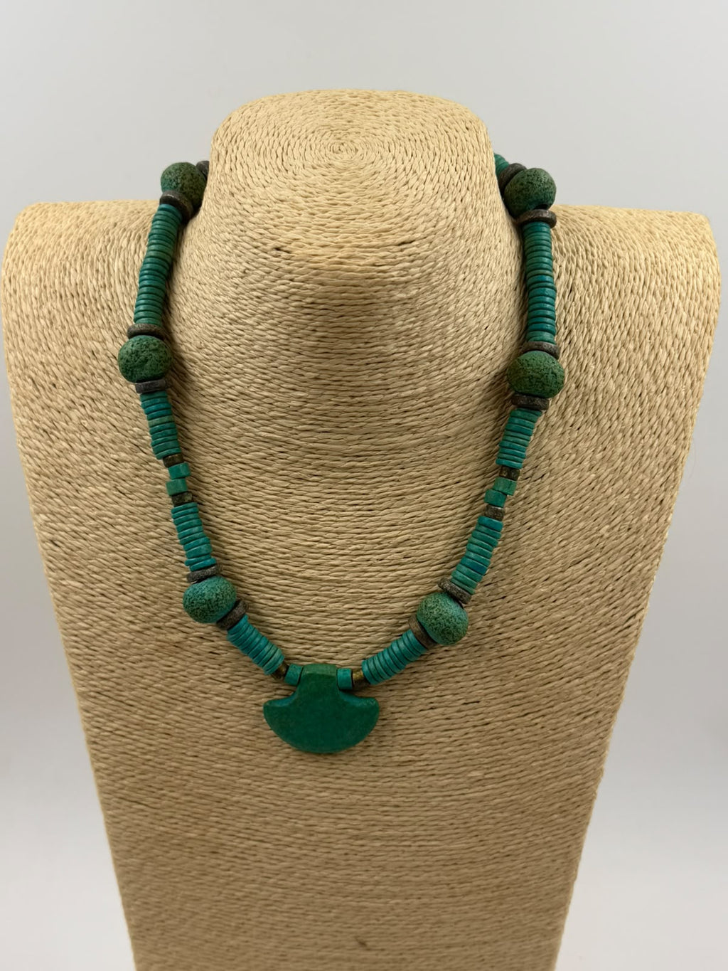Fan shaped natural turquoise pendant close-up showing rough texture and deep teal-green color