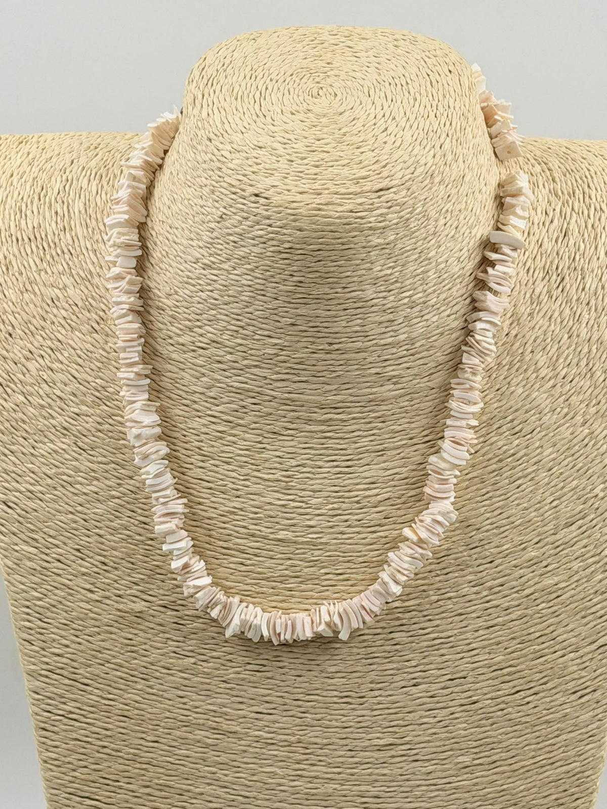 Natural pink shell slice necklace displayed on jewelry bust