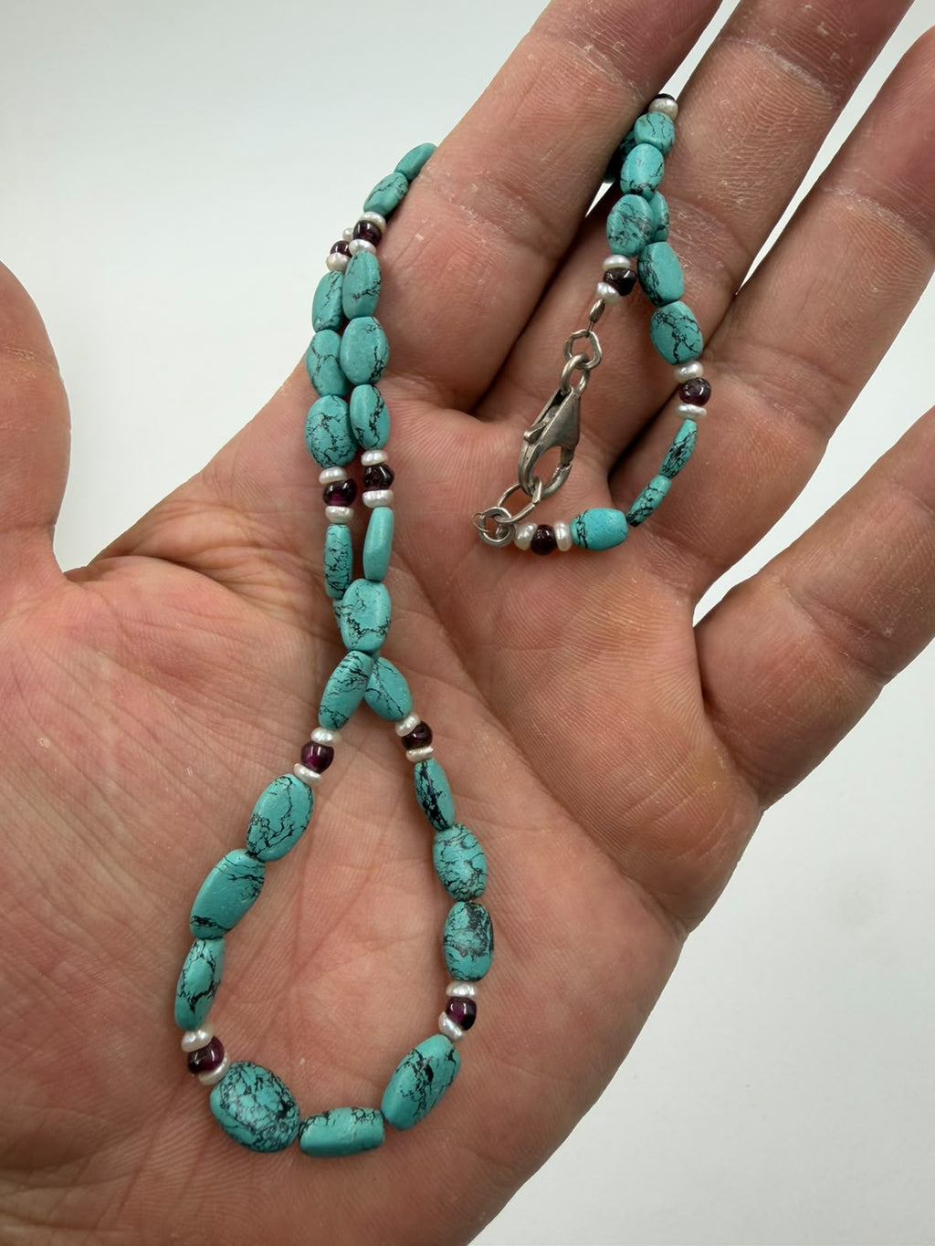 Macro detail of turquoise nuggets garnet cabochon and freshwater pearl beads showing texture