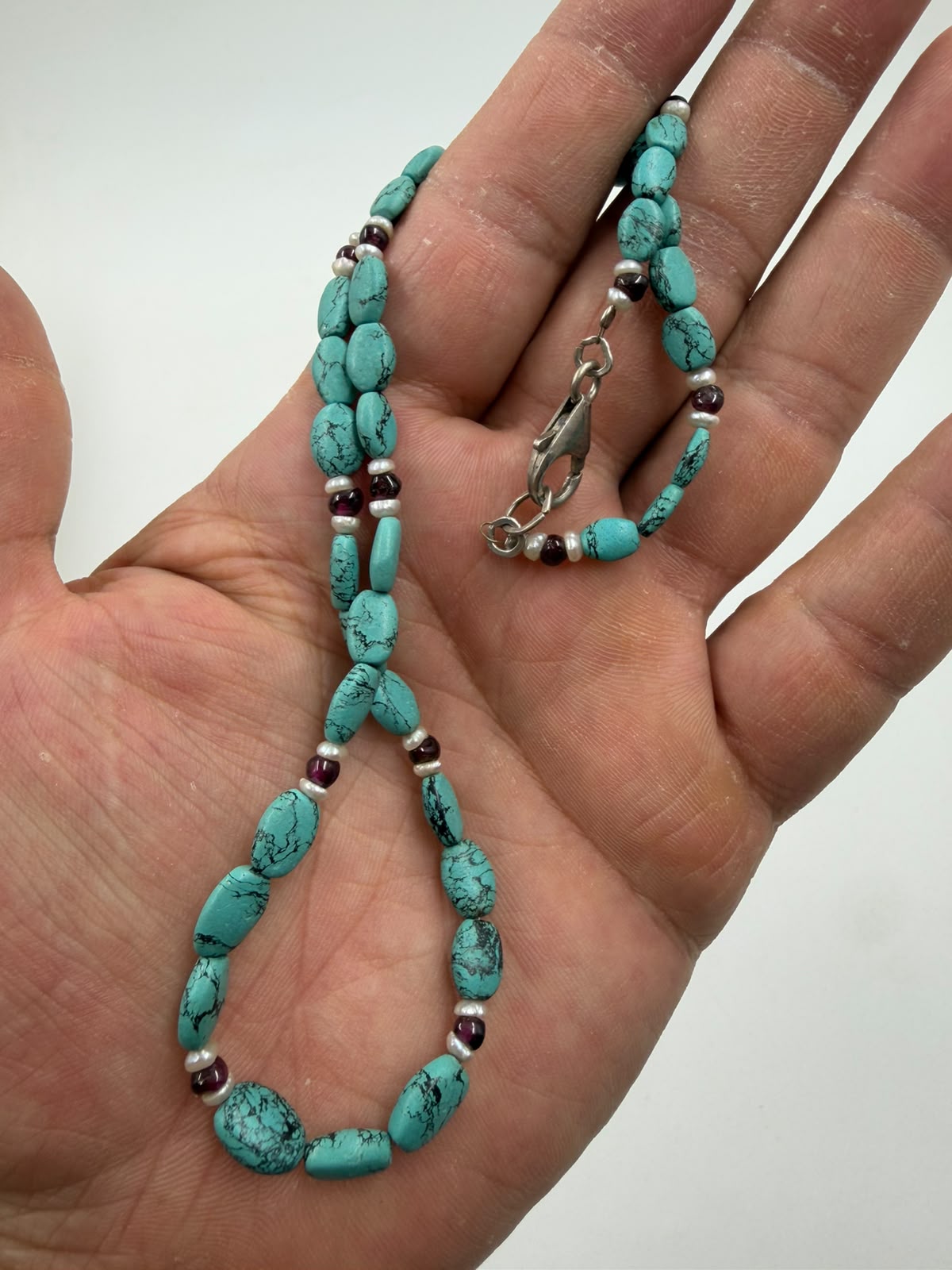 Macro detail of turquoise nuggets garnet cabochon and freshwater pearl beads showing texture