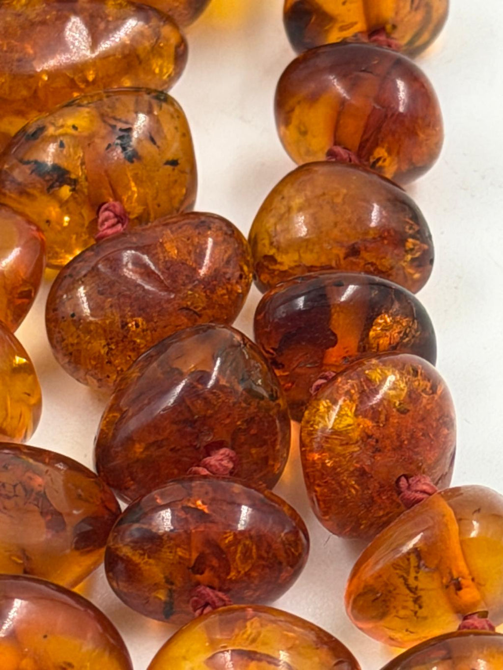 Side view of amber-like necklace on display stand
