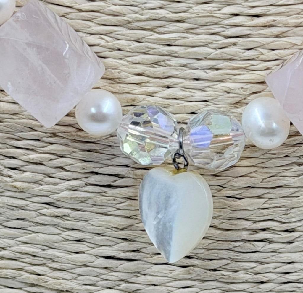Rose quartz pearl necklace held in hand showing heart pendant