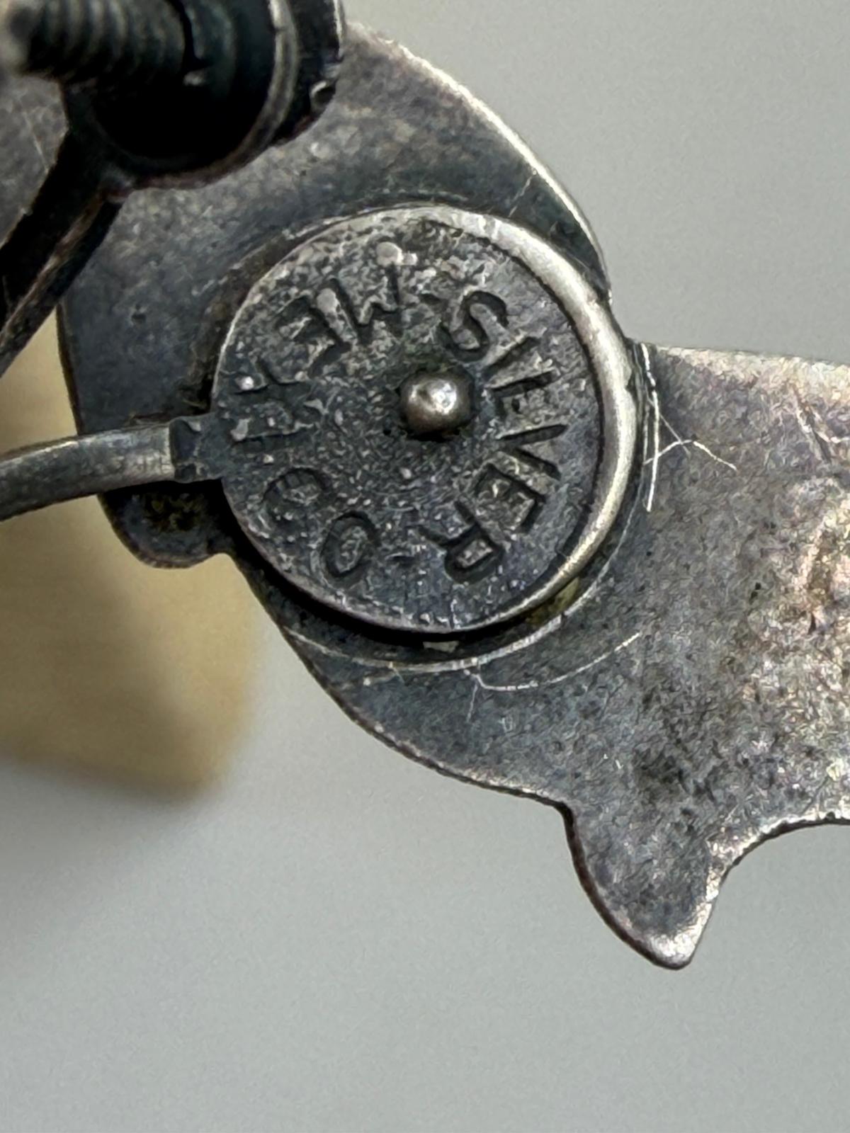 Pair of parrot earrings held in hand showing size