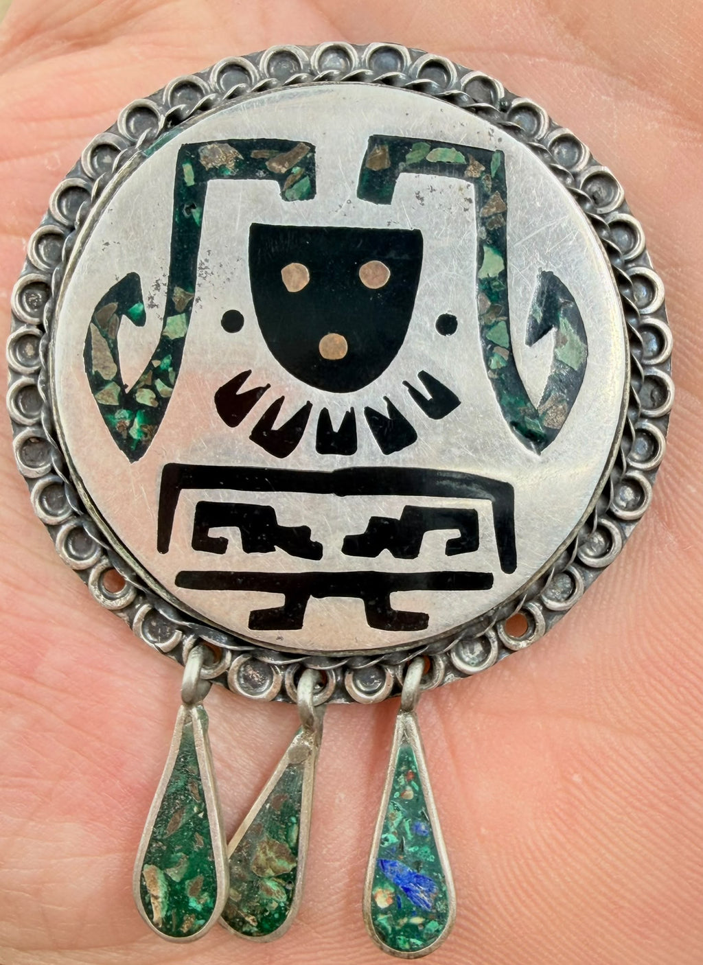 Vintage Mexican silver brooch held in hand - front
