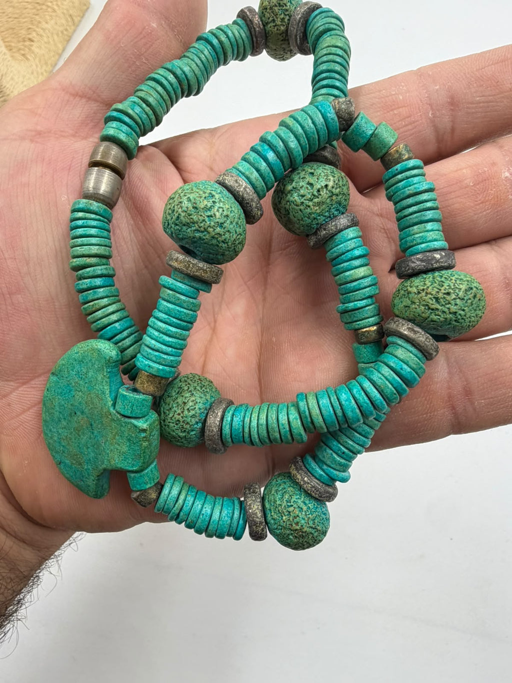 Close-up of natural turquoise heishi disc beads and oxidized bronze spacers showing antique texture