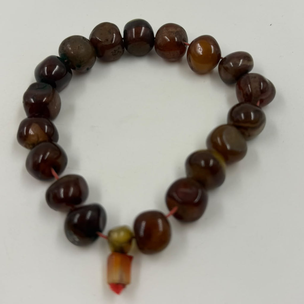 Natural red agate tumbled beads held in palm showing full bracelet pile with honey-green stopper bead