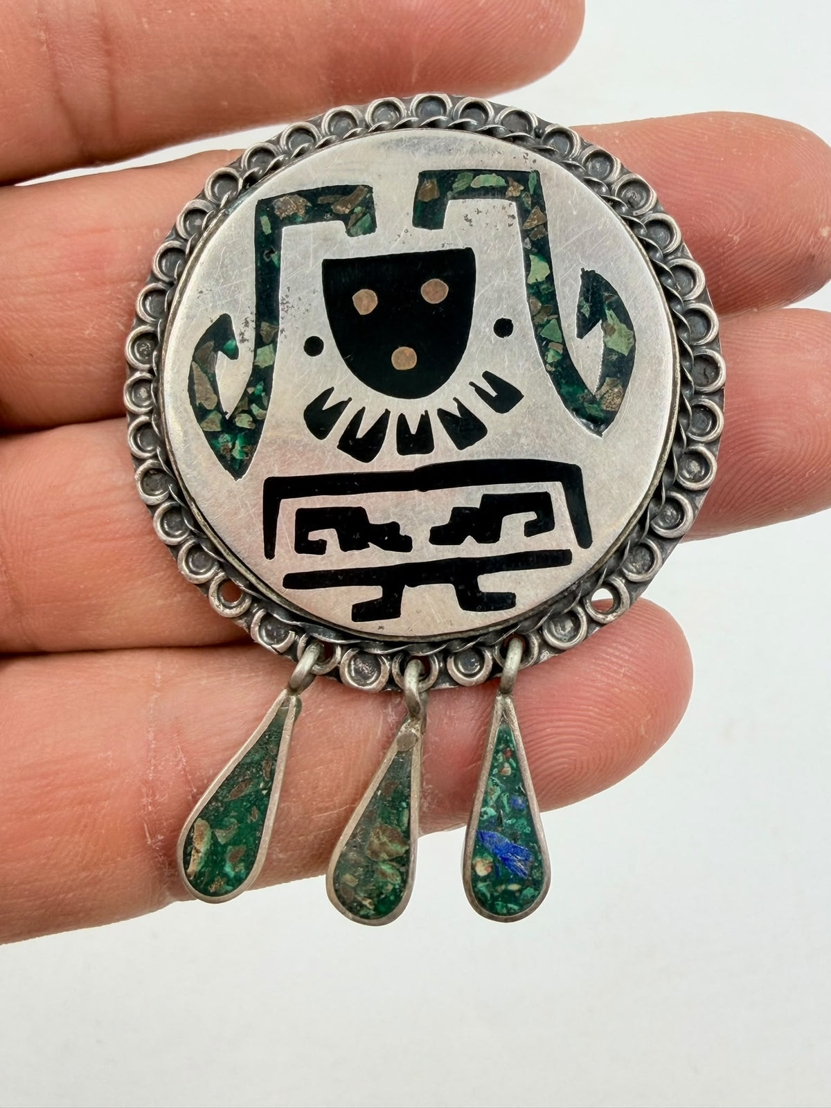 Vintage silver brooch held in hand - side view