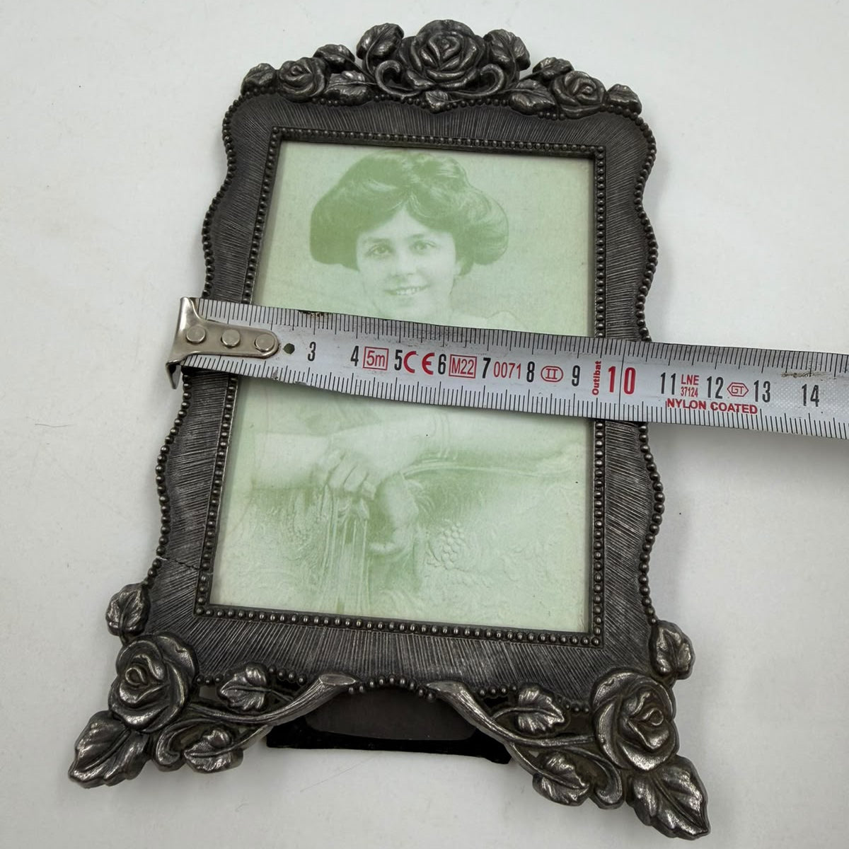 Oval pewter photo frame with ruler showing 14cm width