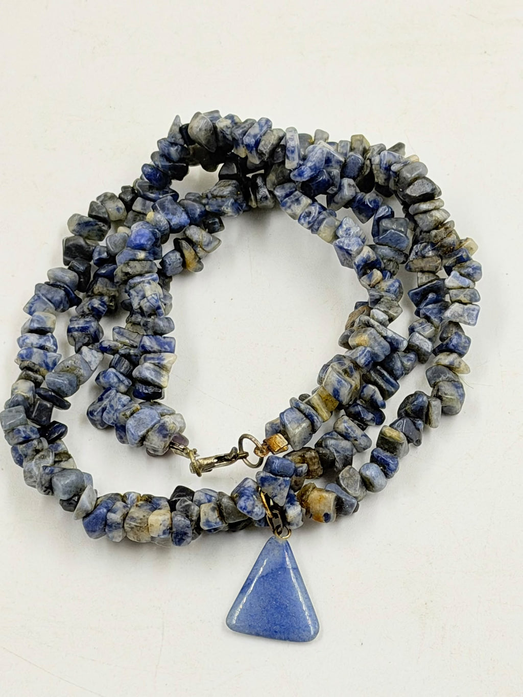 Natural sodalite triangle pendant close up showing smooth blue matte finish