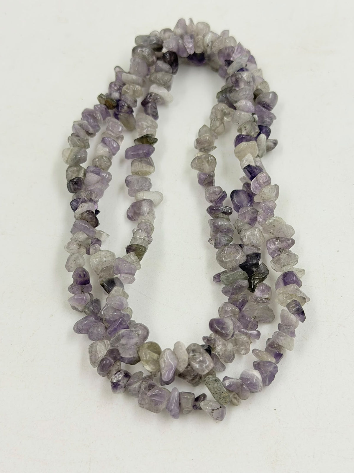 Natural amethyst chip necklace on wicker bust - front view grey background