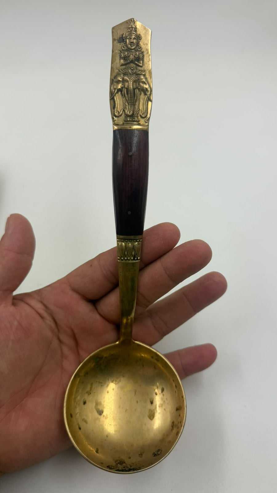 Antique Thai brass ladle held in hand – size reference
