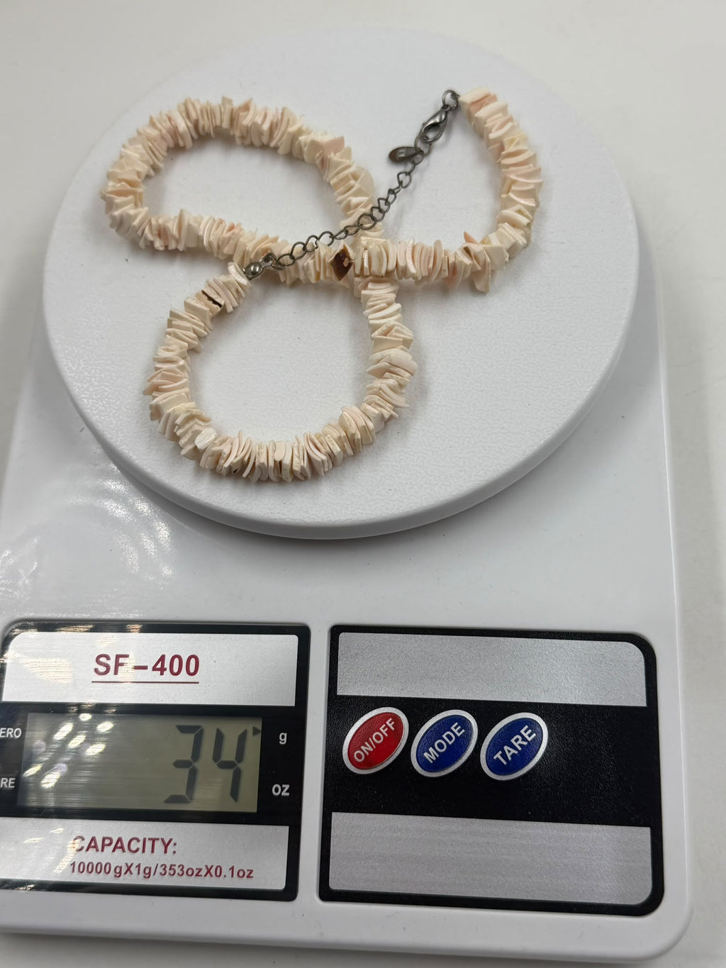 Pink shell necklace on scale showing 34 grams weight