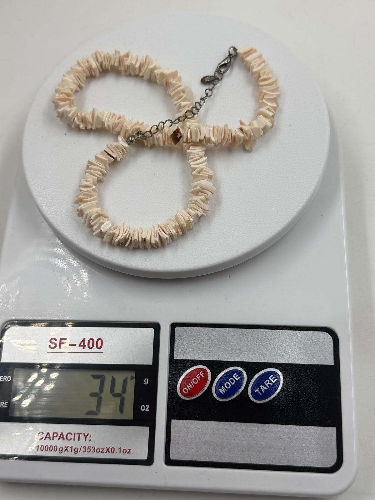 Pink shell necklace on scale showing 34 grams weight