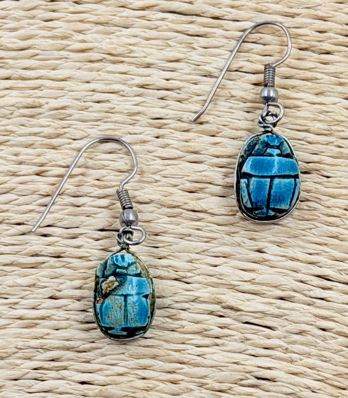 Pair of scarab earrings held in hand showing scale
