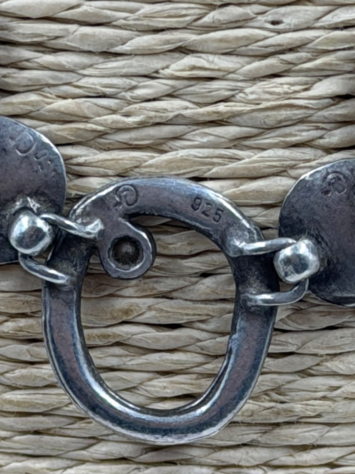 Close-up of spiral circles and CZ stones on oxidized silver necklace in hand