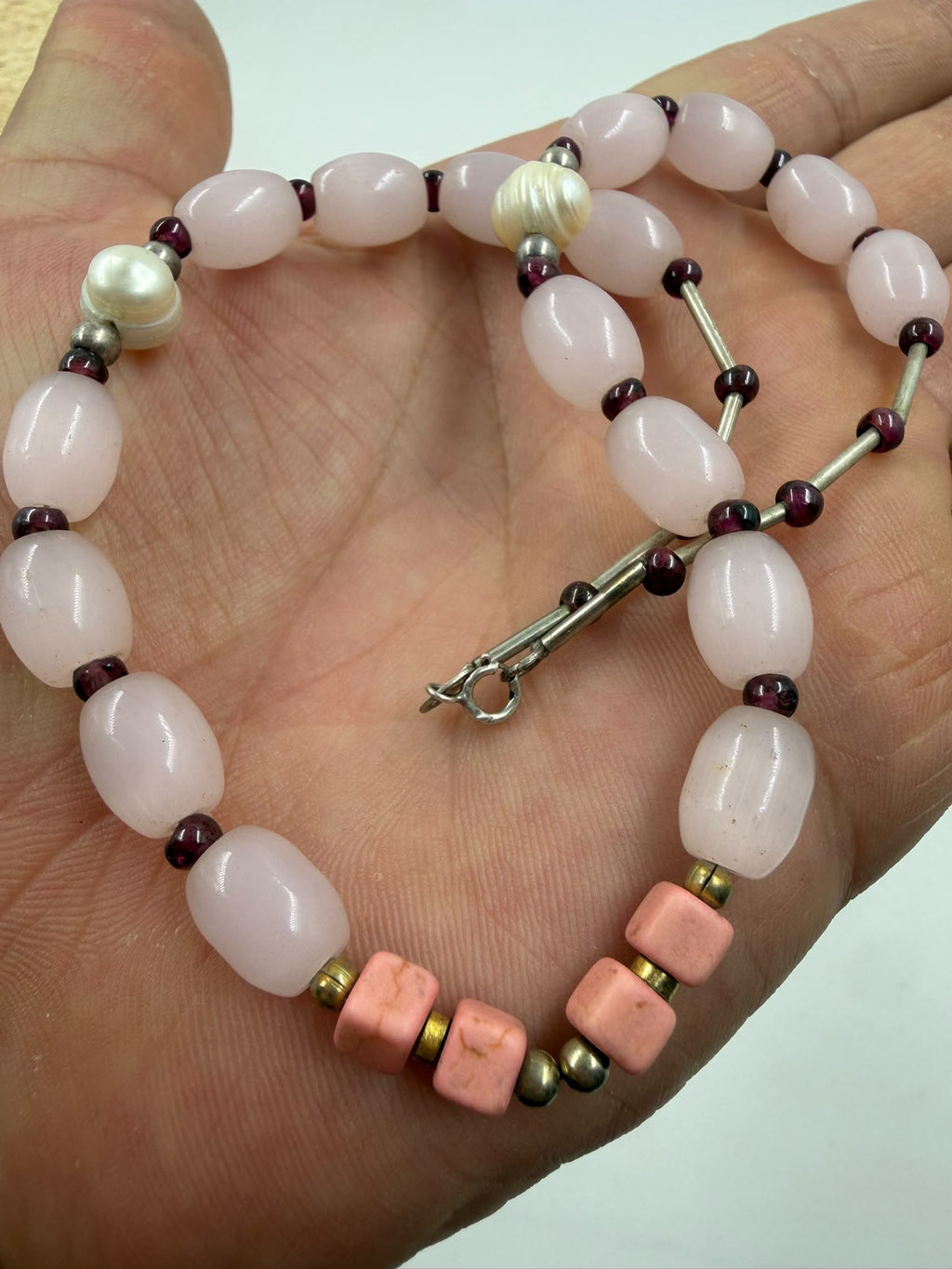 Rose quartz bracelet in hand showing pink coral cube beads garnet seed beads and freshwater pearl accents
