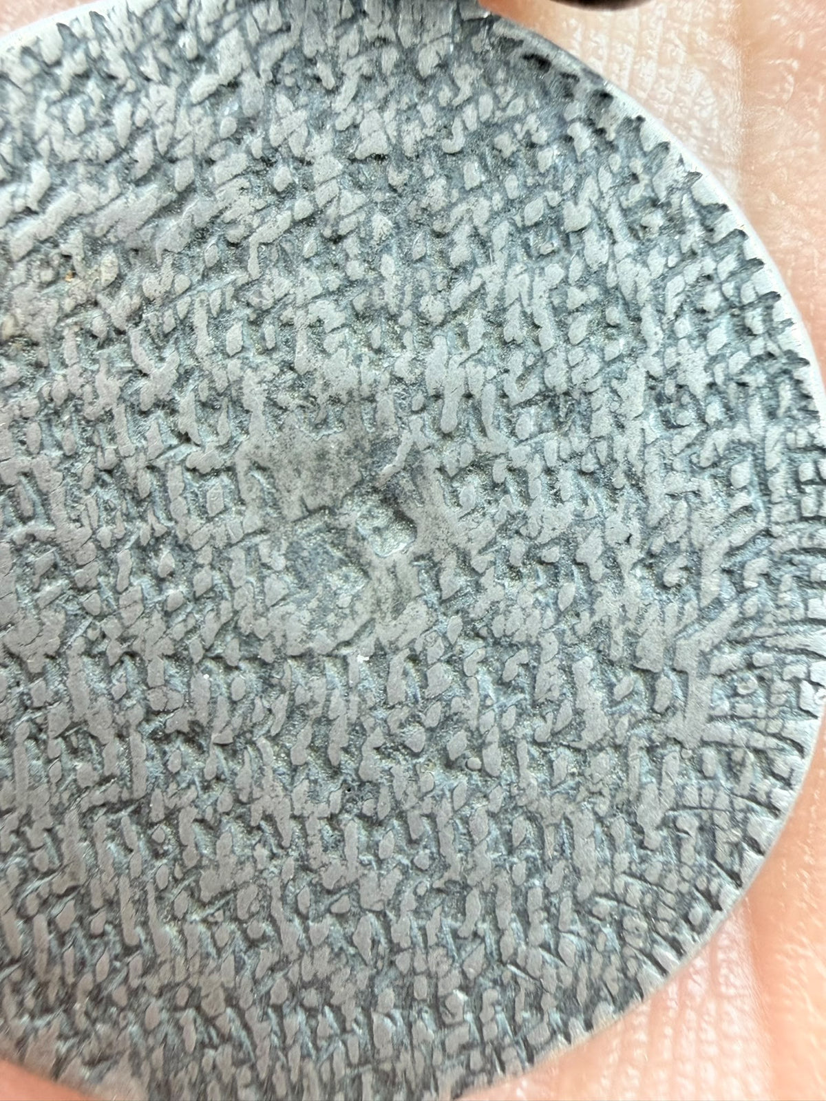 Back of 800 silver antique coin pendant in hand showing textured surface