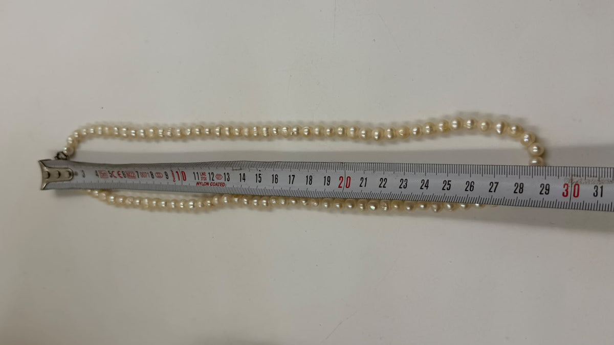 Freshwater pearl necklace held in palm showing full length 58cm and lobster claw clasp