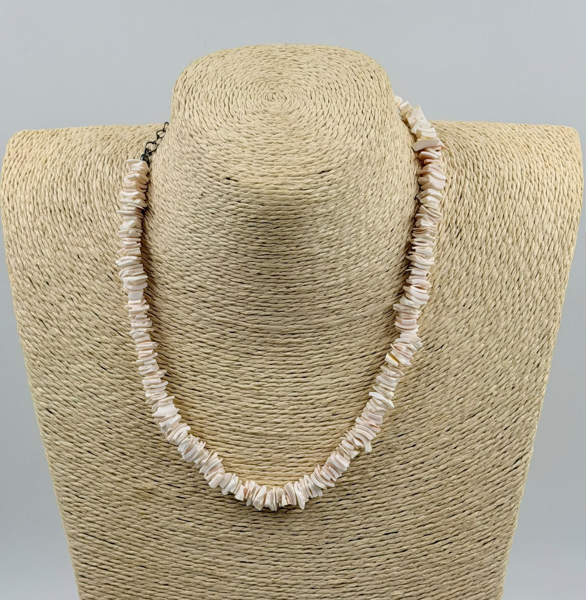 Natural pink shell slice necklace laid flat on white background