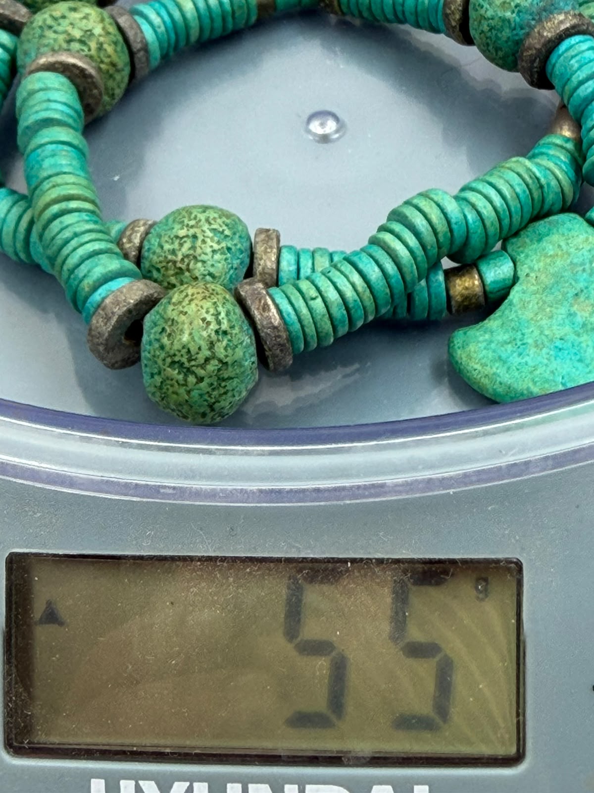 Turquoise tribal necklace on scale showing weight 55 grams with heishi and nugget beads visible