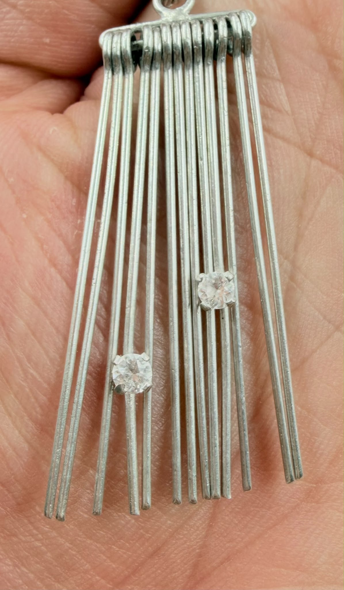 Single earring close-up showing coiled top bar and crystal stones