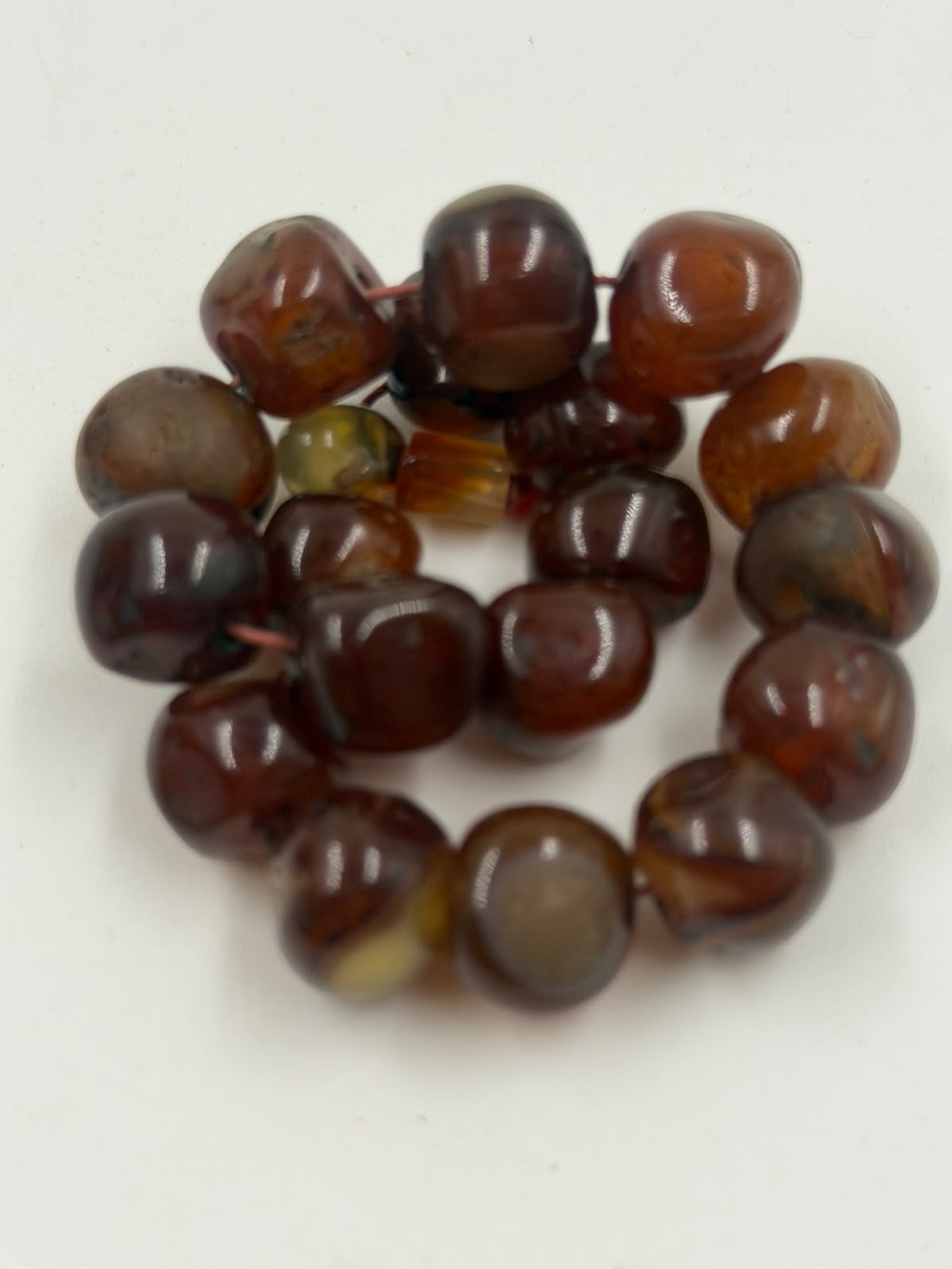 Natural red agate suleimani tumbled bracelet on bust display showing full round shape with honey-green stopper bead