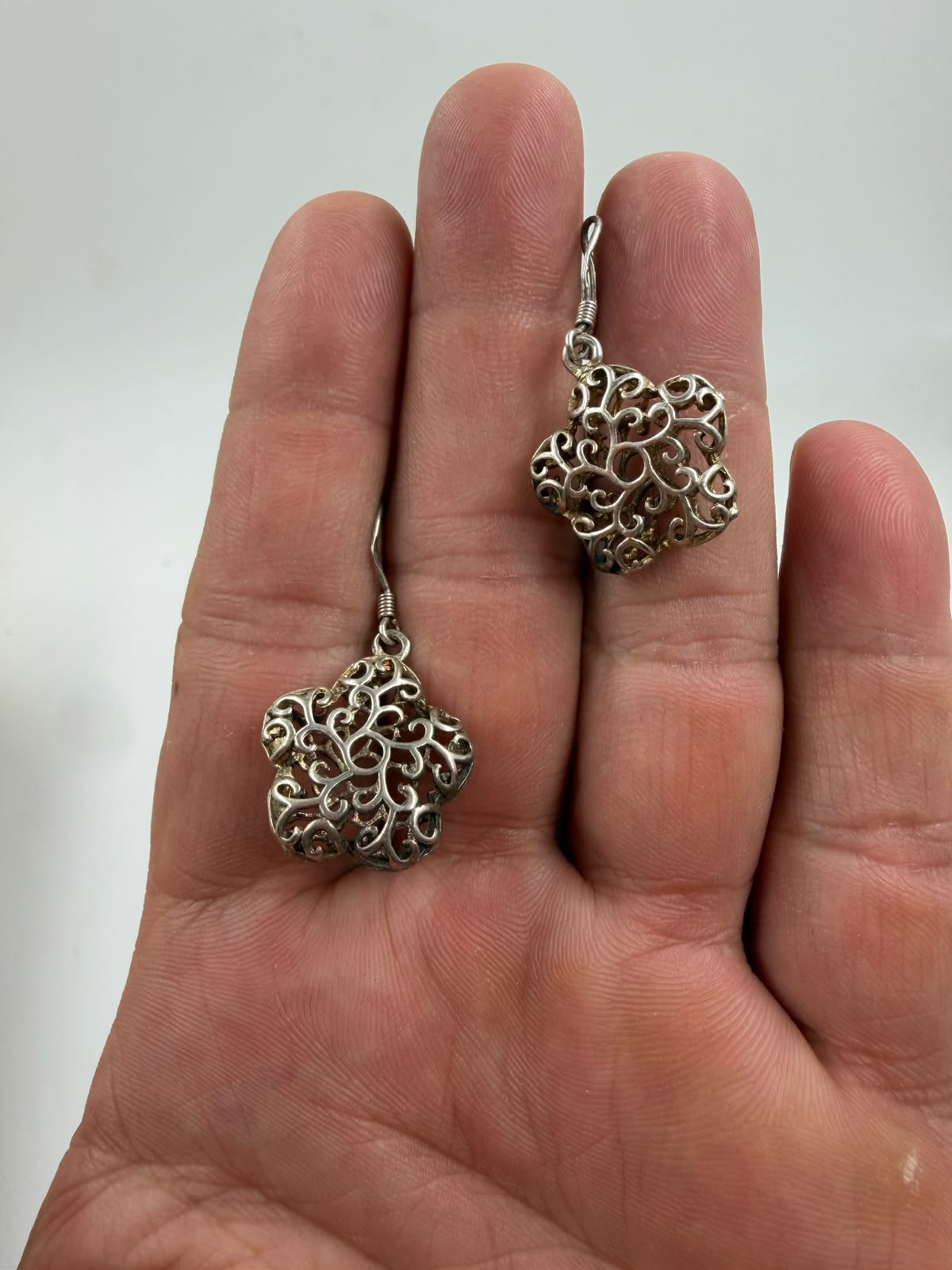 925 silver filigree flower earrings on woven display showing oxidized dark patina contrast