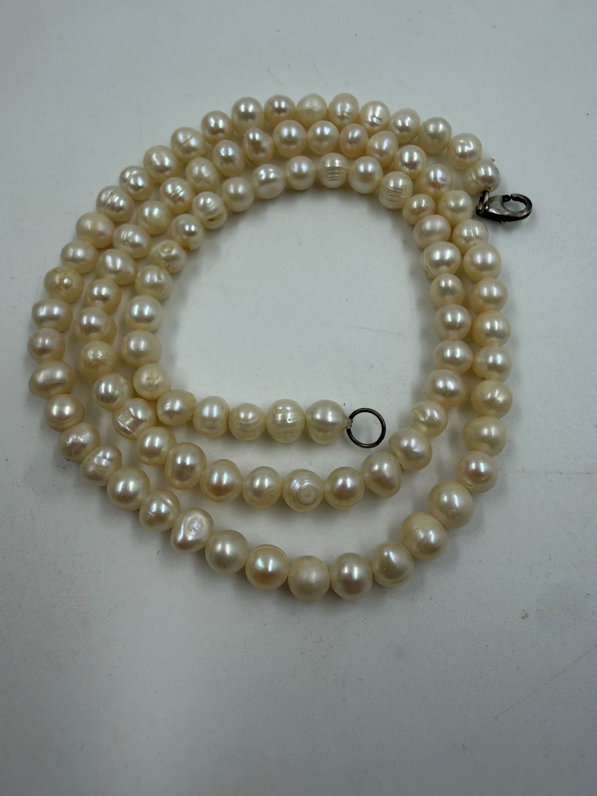 Close-up of freshwater pearl beads on wicker surface showing baroque shape surface texture and rose-silver overtone