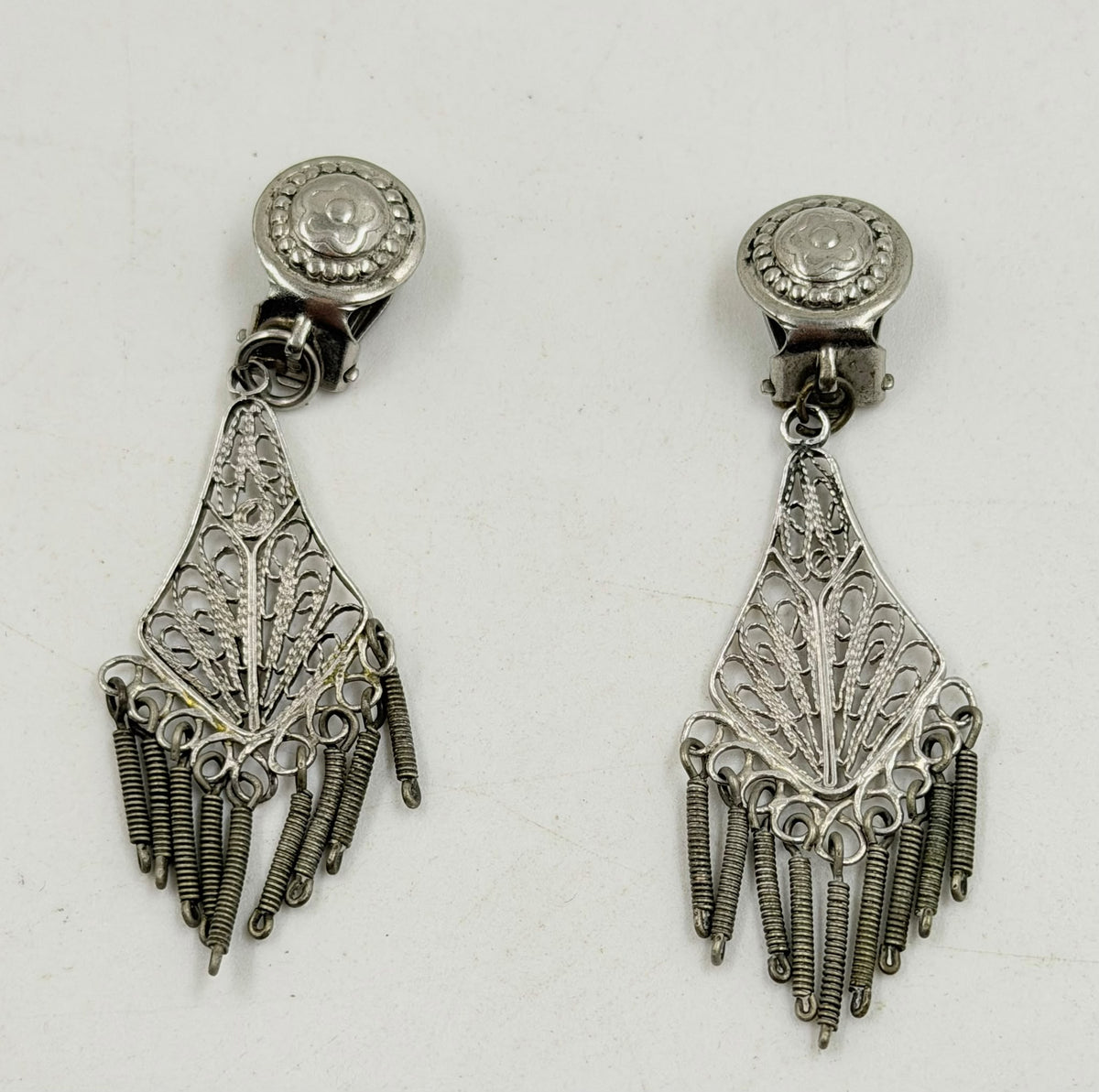 Silver filigree earrings pair on rattan background showing full length