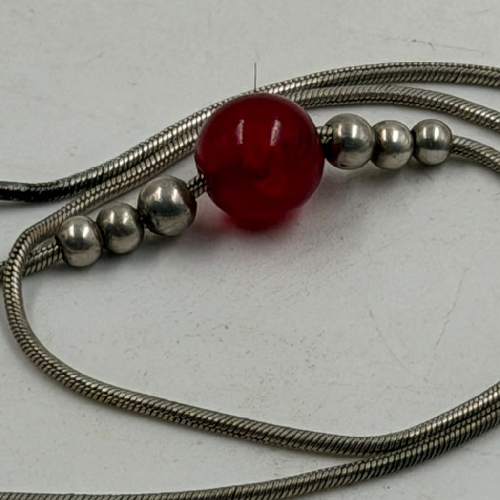 Close-up of red carnelian bead on silver snake chain