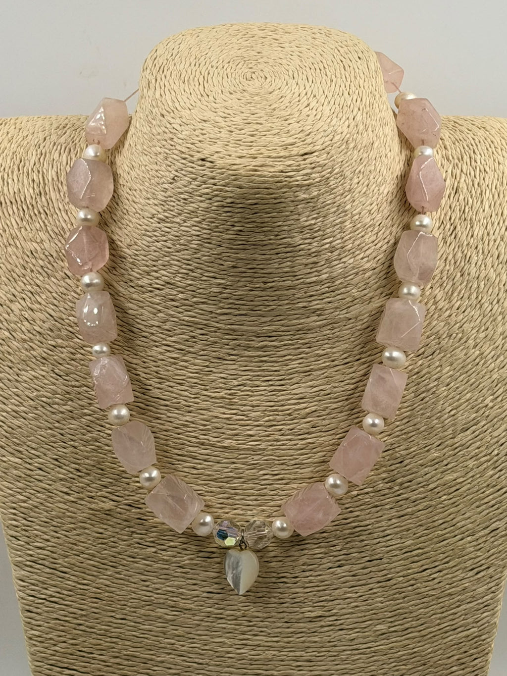 Rose quartz pearl necklace laid flat in circle on white background