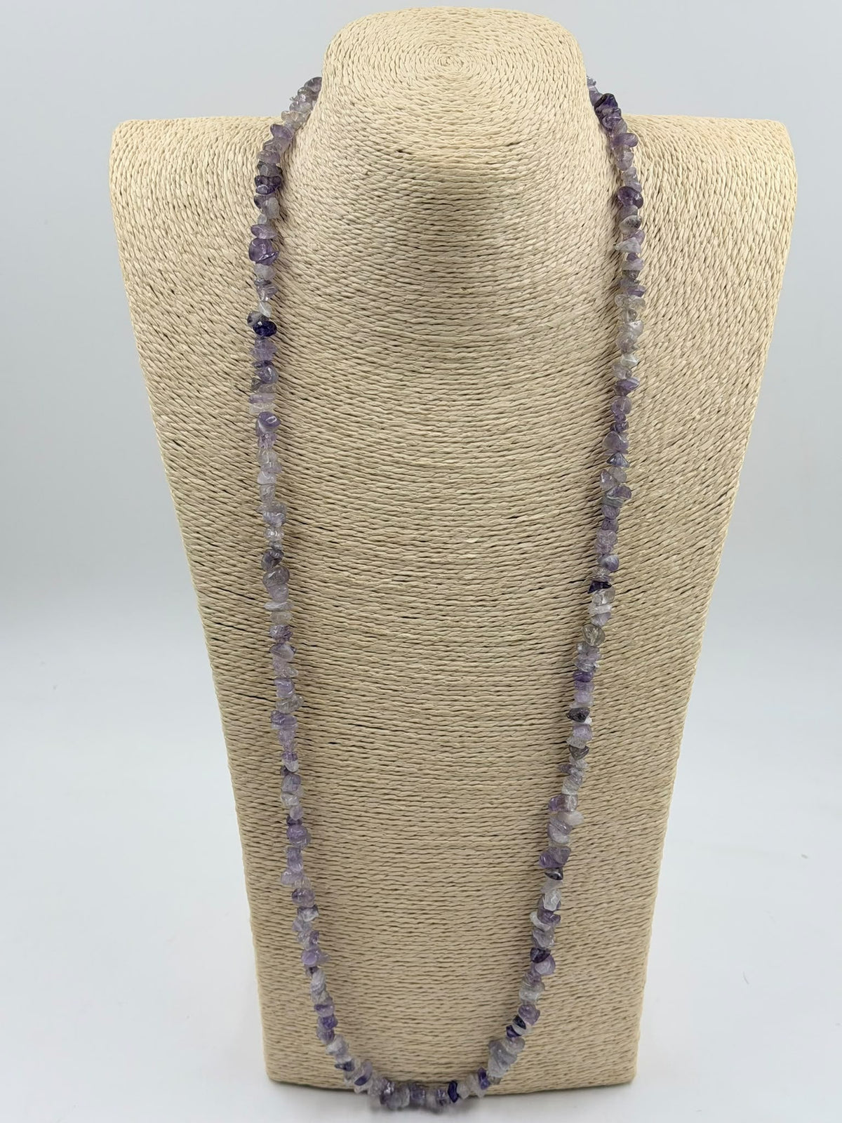 Natural amethyst chip necklace coiled on white surface